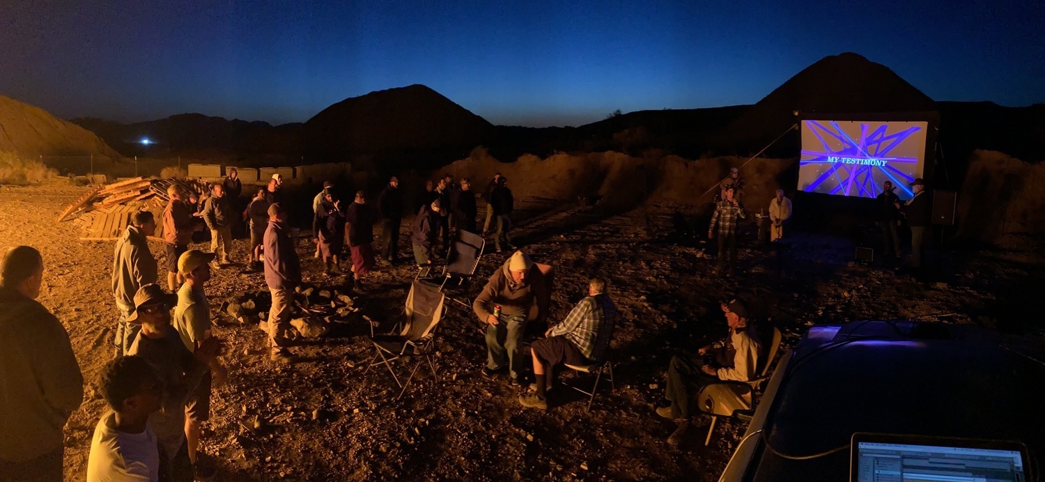 Campfire group watching a movie outdoors
