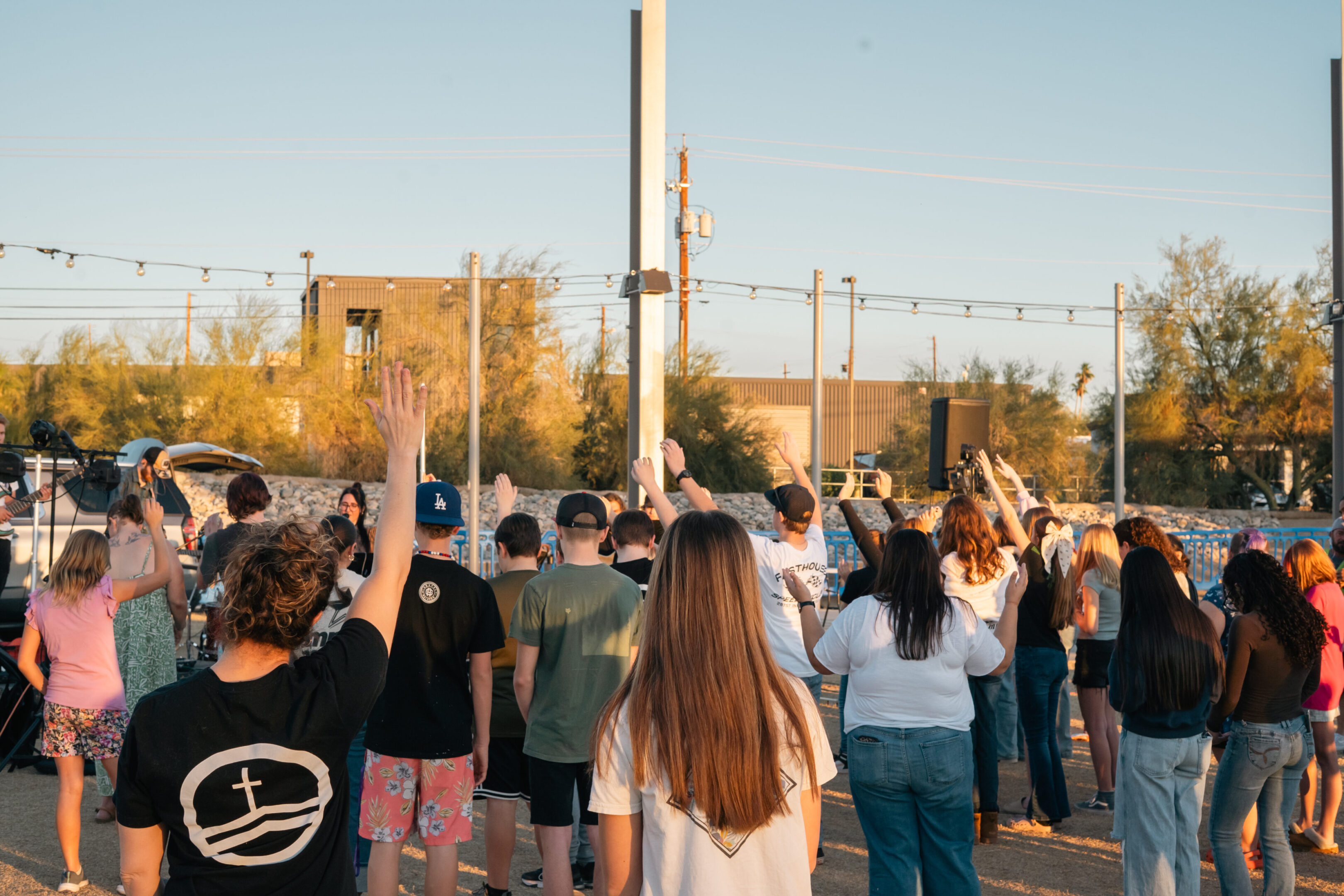 A group of people raising their hands outdoors during daylight.