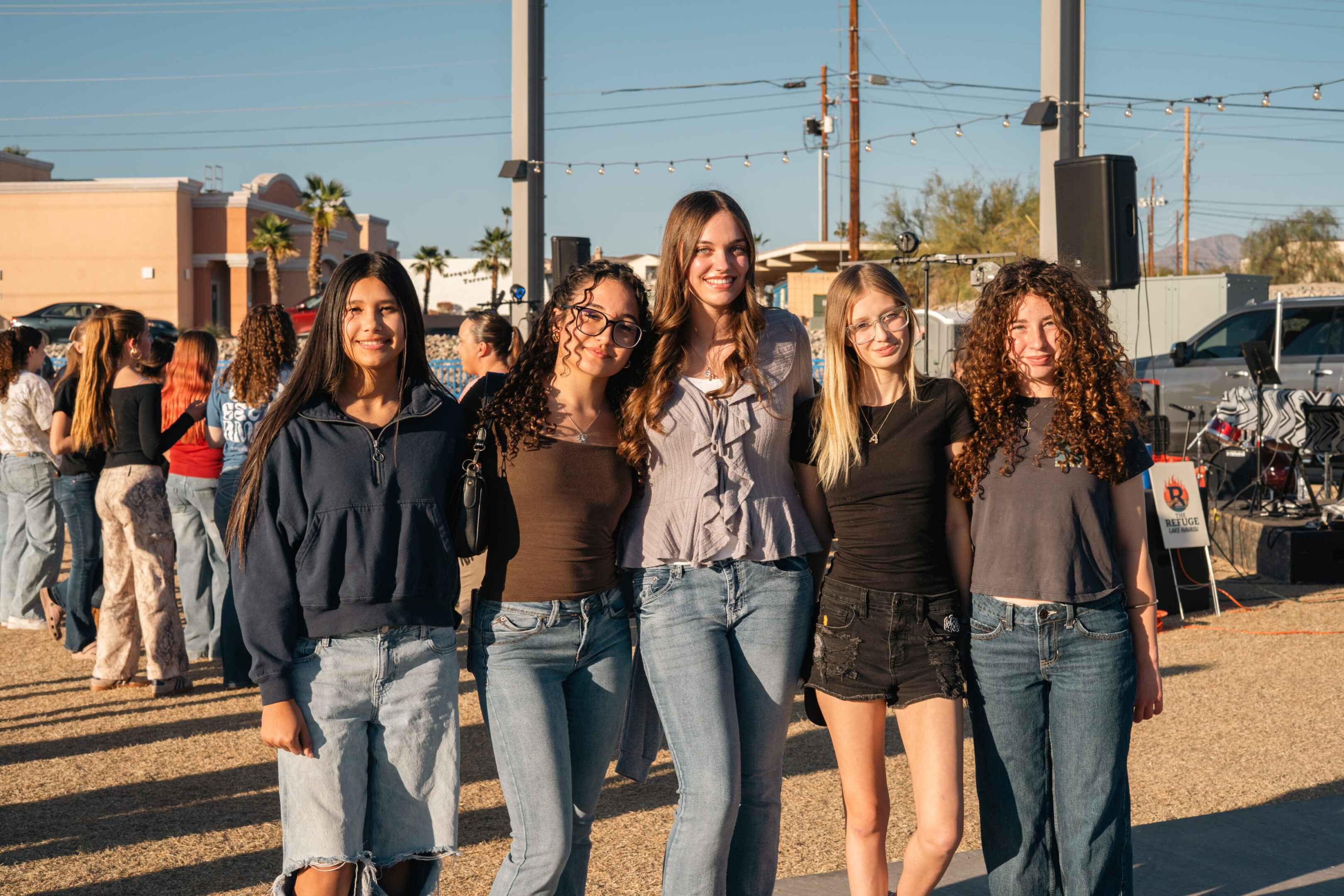 Five young women posing outdoors on a sunny day.