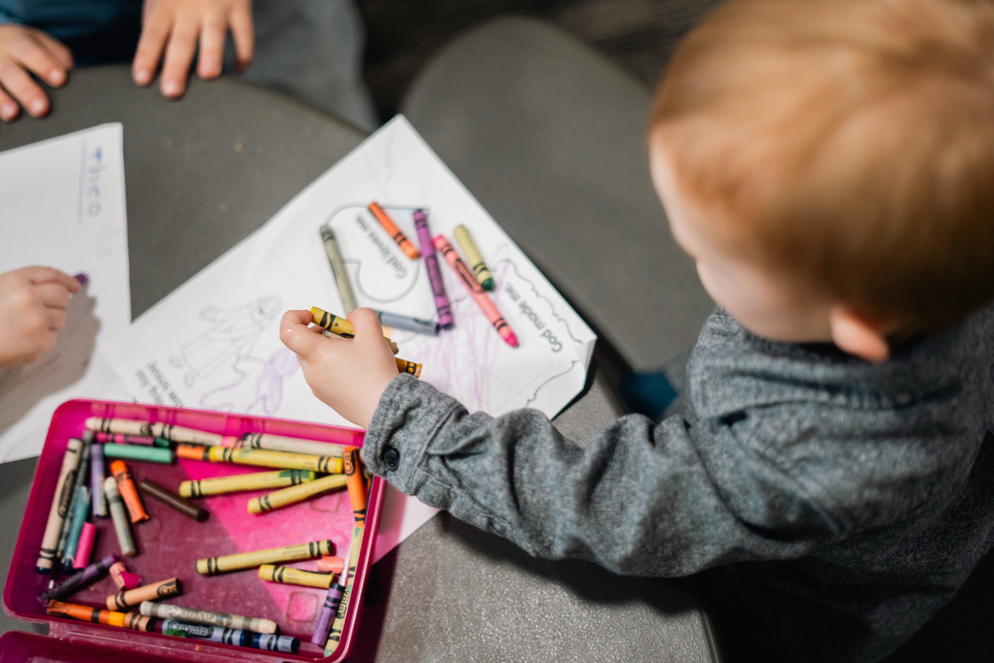 A child coloring with crayons on paper.